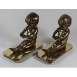 A pair of Hailware brass models of seated children Raised on plinth bases, height 20cm.