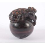 NETSUKE SHISHI AUF BALL MIT ONI-KOPF, Kurogaki-Holz, Augen des Shishi aus hellem Horn mit dunkler