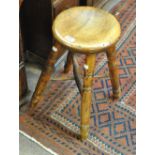 A 19th century elm and beech stool with dished circular top and four outswept ring turned legs