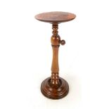 A Victorian walnut adjustable candle stand with circular top above baluster ring turned central