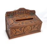 A late Victorian carved oak wall mounted letter box, the shaped back rail inscribed 'Letters',
