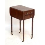 A mahogany and inlaid work table with two drawers to either side on ring turned legs to castors,