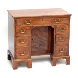 A George III mahogany kneehole desk with recessed central cupboard within an arrangement of drawers