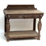 A late Victorian carved oak two drawer side table with raised back, mask detail,