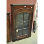 A mahogany flat fronted corner cupboard with dentil moulded cornice above arched glazed doors