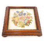 A Victorian rosewood tea board with central glazed needlework floral decorated panel,