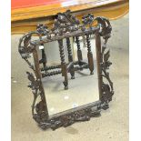 An early 20th century Black Forest type carved beech wall mirror decorated leaves and flower heads,