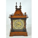 A circa 1900 German oak cased mantel clock with caddy top above brass base with circular dial,