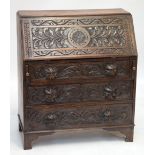 A late Victorian carved oak bureau, with three drawers to the base and sparsely fitted interior,