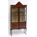 An Edwardian mahogany display cabinet with shaped pediment above pair of glazed door enclosing four