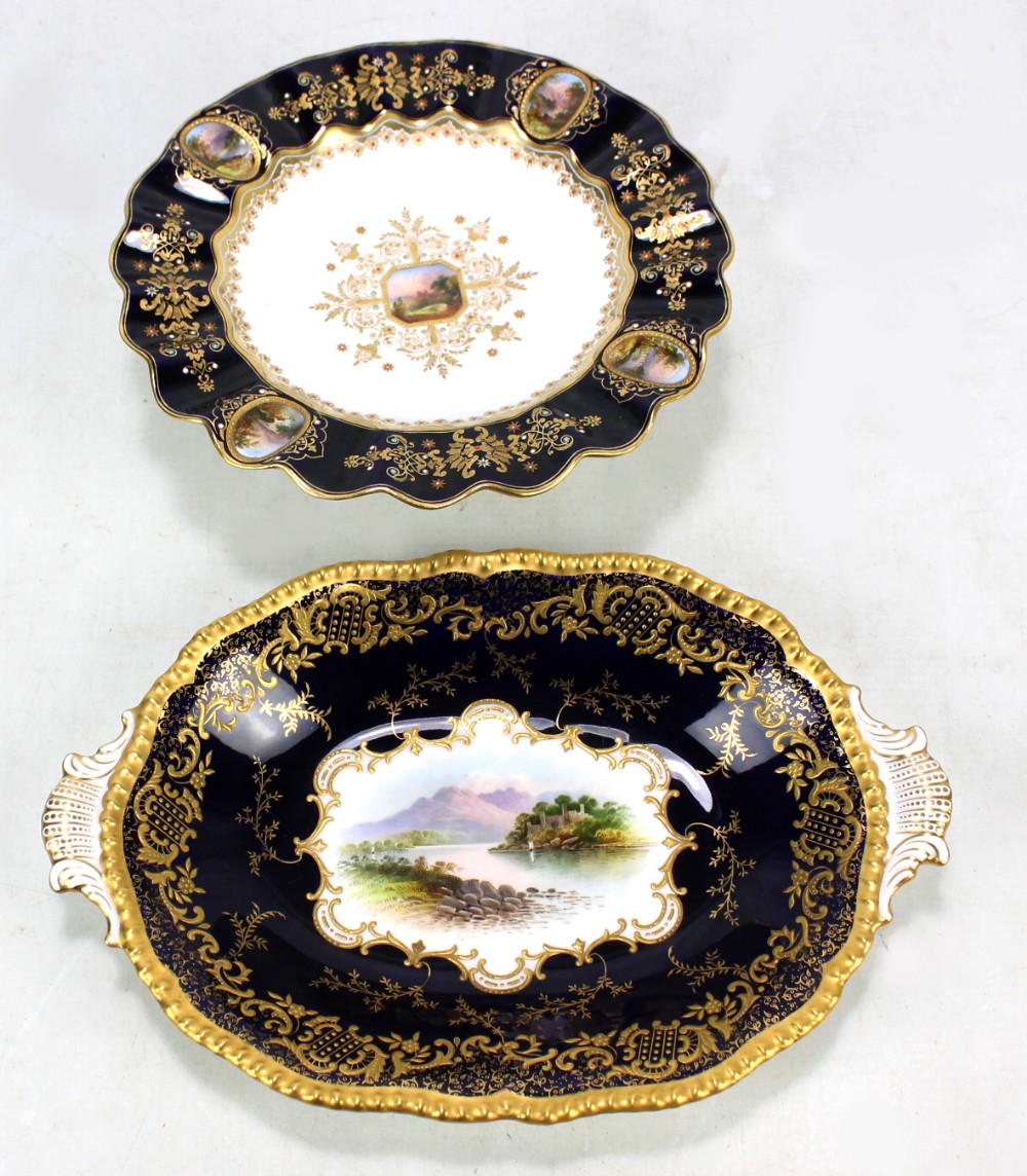 A Coalport 'Jewelled' landscape decorated gilt heightened tazza with scallop moulded dark blue