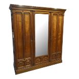A circa 1900 oak three door wardrobe, the castellated cornice above central mirrored door with six