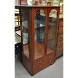 A modern display cabinet with pair of glazed doors above two drawers.