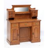 An Edwardian oak desk with raised mirrored back flanked by two banks of two short drawers above