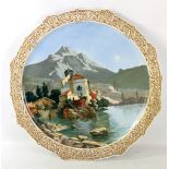 A large Continental porcelain circular charger painted with Alpine scene with castle to the