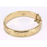 A 9ct yellow gold hollow snap bangle with engraved foliate scroll motifs, with safety chain,