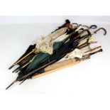 A collection of walking sticks, canes and umbrellas including two ivory capped examples, a horn