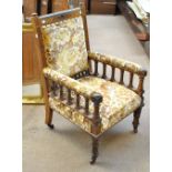 A late Victorian walnut Aesthetic Movement armchair with carved detail raised on ring turned front