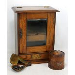 An oak smoker's cabinet with tobacco jar and single cased pipe.