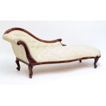 A Victorian mahogany chaise longue with button cream upholstery, carved foliate scroll detail and