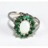 A 9ct white gold cluster ring centred with an oval opal cabochon within a border of twelve round cut