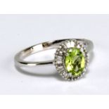 A 9ct white gold ring set with oval cut green peridot within a border of numerous baguette cut