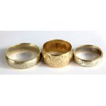 Three 9ct yellow gold wedding bands with engraved decoration, the largest size V1/2, approx 13.1g (