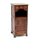 An oak bed side table with compartmentalised drawer above shelf and single door decorated with