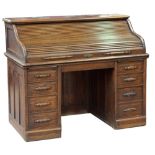 An early 20th century oak roll top desk, with tambour front enclosing a fitted interior above twin