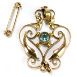 An Edwardian unmarked yellow metal openwork foliate scroll pendant set with two blue coloured