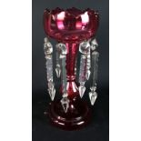 A cranberry glass table lustre with traces of floral and gilt decoration suspending eight drops,