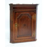 An early 19th century oak and mahogany crossbanded flatfronted corner cupboard.