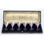 CHARLES EDWARDS; a cased set of six George V hallmarked silver conical tot cups, with gilt