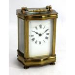 A circa 1900 brass carriage clock with serpentine sides, on turned brass supports, the rectangular