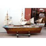 A large wooden four masted model ship with painted decoration, metal cannons and stands, crewmen