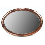 An Arts and Crafts hammered copper oval bevelled wall mirror, 53 x 77cm.