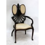 An Edwardian mahogany framed cream upholstered armchair with shaped and pierced back.