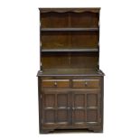 A reproduction dark oak dresser of small proportions, the closed back with two shelves above two