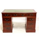 A reproduction mahogany twin pedestal desk with inset green leather writing surface above