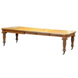 An Edwardian golden oak extending dining table, the top with canted corners above acanthus carved