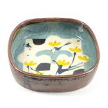 JOHN MALTBY (born 1936); a square stoneware dish decorated with a stylised landscape, painted