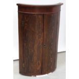 A George III oak bow-front corner cabinet with mahogany cross-banding and veneered frieze,