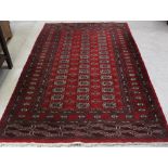 A red ground Bokhara carpet with multiple gul decorations within a geometric multi-border,