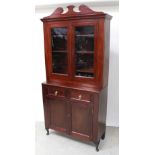 A contemporary cabinet bookcase, broken swan neck pediment over two glazed doors,