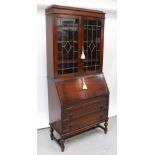 A 1920s stained oak bureau bookcase, the twin doors with leaded lights,