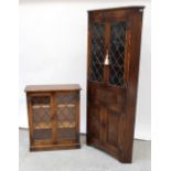 A floor-standing oak corner unit with leaded upper section over single frieze drawer,