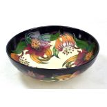 MOORCROFT; a navy and cream ground 'Anna Lily' pattern tubeline decorated footed bowl with impressed