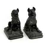 A pair of carved serpentine seated dogs on rectangular bases with canted corners, height 25cm (one