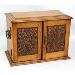 An oak smoker's cabinet, the two doors with carved panels enclosing fitted interior (no additional