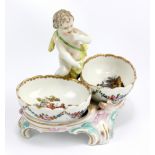 BERLIN PORCELAIN; a late 19th/early 20th century figural salt in the form of a putto and raised on